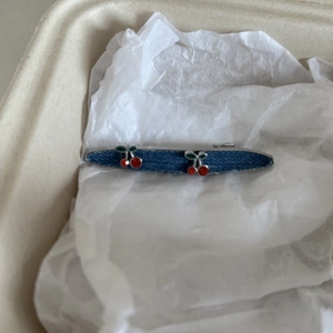 Detail view of denim hair clip featuring 3D cherry charms on a blue fabric base