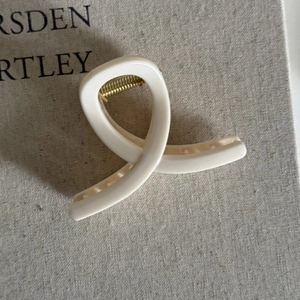 Detailed view of cream-colored resin shark hair claw clip with golden metal spring