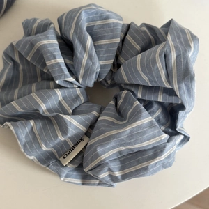 Close-up of blue and white striped fabric scrunchie with a small brand tag detail