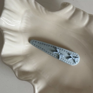 Detailed view of light blue fabric hair clip with cute 3D bowknot and stitched edges