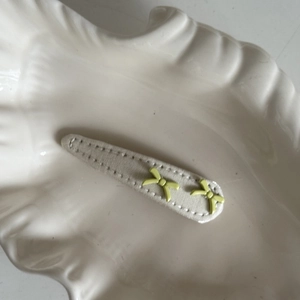 Detailed macro view of beige fabric BB hair clip with decorative lime green bows