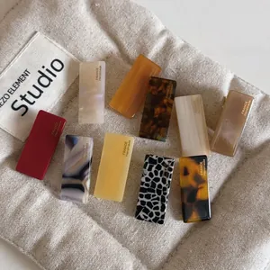 Macro shot of high-quality colorful acetate hair clips with gold label on beige fabric