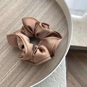 Chouchou élégant en satin caramel avec finition soyeuse sur un plateau blanc chic