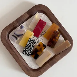 Mini acetate baguette hair clips in various patterns and colors on a wooden tray