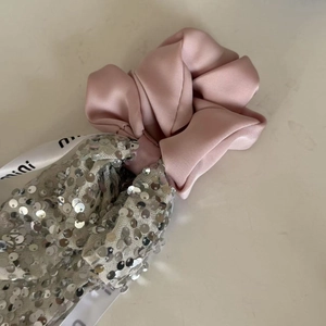 Detail of pink satin scrunchie with silver sequins and decorative printed ribbon