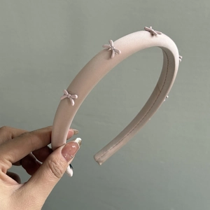 Detailed close-up of a sweet pink satin headband with 3D bow decorations and sponge padding