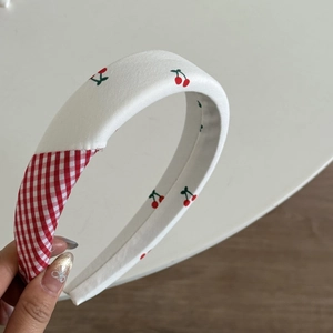 Dettaglio di un cerchietto imbottito con stampa ciliegia e patchwork in tessuto vichy