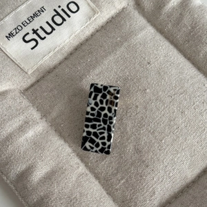 Macro detail of rectangle acetate hair clip with black and white giraffe print texture