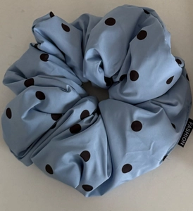 Dettaglio di elastico per capelli azzurro a pois con etichetta fashion e pizzo