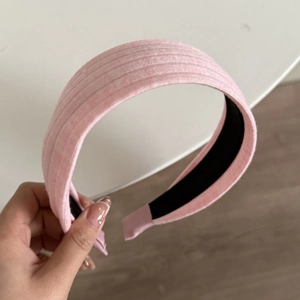 Detailansicht eines rosa Stoff-Haarreifens mit vertikalen Streifen und schwarzem Innenfutter