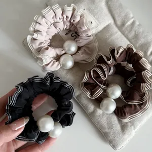 Détail de chouchous plissés avec perles en noir, marron et beige doux