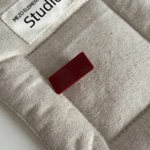 Macro view of dark red acetate baguette hair clip with gold France Handmade lettering