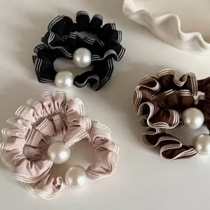 Chouchous en dentelle avec perles en noir, marron et rose sur un plateau en céramique