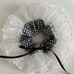 Detail of checkered hair scrunchie with white lace trim and a black ribbon bow