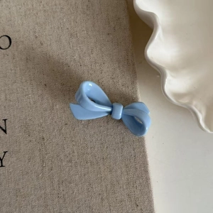 Elegant sky blue acrylic bow hair clip for women with glossy finish on textured fabric
