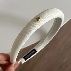 Détail du serre-tête en tissu blanc avec mousse épaisse et étiquette dorée faite main