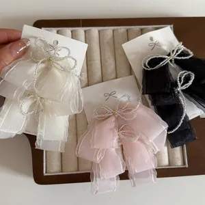 Detailed close-up of beaded ribbon hair clips in white, pink and black on velvet tray