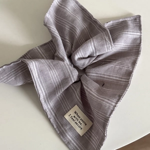 Détail d'un chouchou en tissu violet à carreaux avec rayures blanches et étiquette tissée