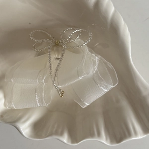 Elegant white beaded bow hair clip with organza ribbon displayed in a shell tray