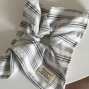 Détail d'un chouchou à rayures noires et blanches avec étiquette tissée sur fond blanc