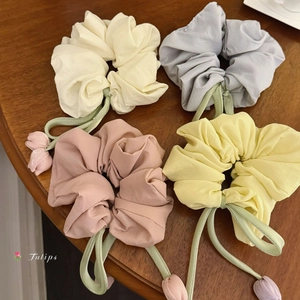 Détail de quatre chouchous sur le thème des tulipes avec breloques sur une table en bois