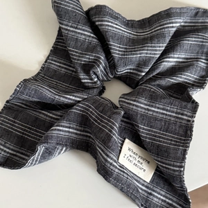 Détail d'un chouchou rayé noir et blanc avec texture textile et étiquette tissée