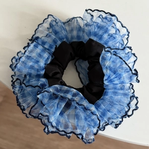 Detailed view of blue grid mesh scrunchie with delicate black floral lace edges