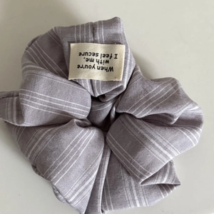 Détail du tissu chouchou à rayures lavande et étiquette tissée sur fond blanc uni