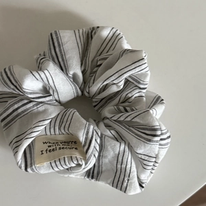 Détail d'un chouchou à rayures avec étiquette décorative sur un bureau blanc épuré