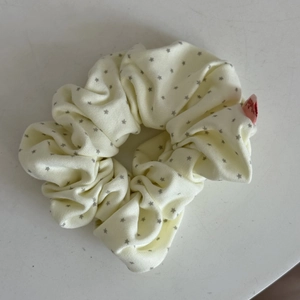 Detail of cream fabric scrunchie with star patterns and a small red brand label