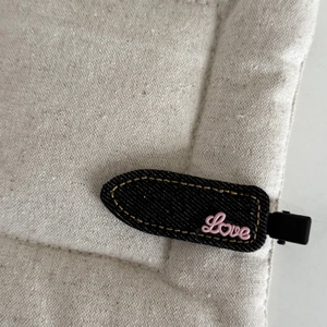 Detailed macro view of denim fabric hair clip with pink 3D Love letter decoration