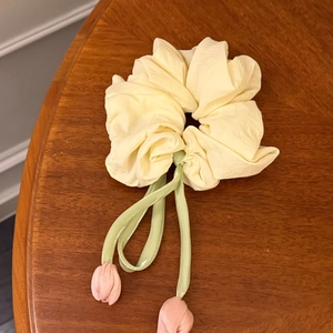 Détail de chouchou tulipe montrant des bourgeons roses et rubans verts sur bois sombre
