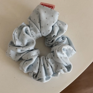 Close-up of blue scrunchie with grey star patterns and pink brand label detail