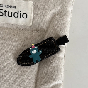 Close-up of denim bow hair clip with cute cartoon bear and yellow stitching details