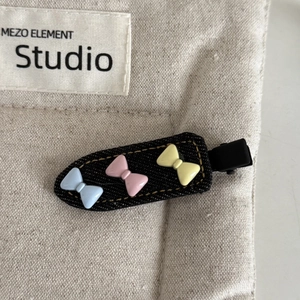 Detail of denim duckbill hair clip with colorful macaron plastic bows on beige canvas