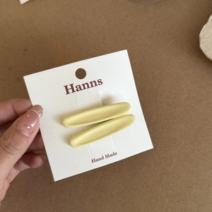 Set of two minimalist matte yellow oval hair clips for women on a white display card
