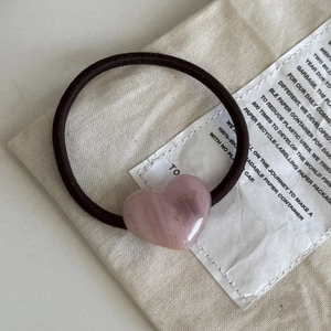 Detailed macro view of a pink heart resin pendant on a brown elastic hair tie