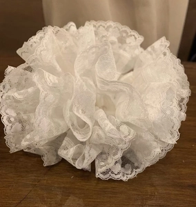 Macro detail of white organza lace hair scrunchie with polka dot texture on wooden table