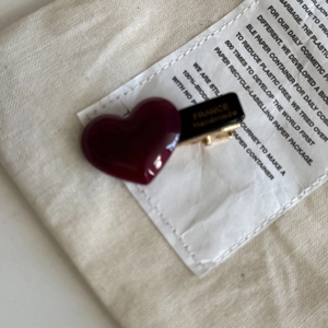 Detailed close-up of dark red heart-shaped acetate hair clip with gold handmade text