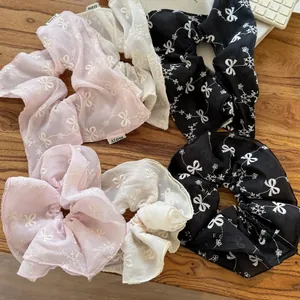 Detail of embroidered chiffon scrunchies with butterfly patterns on wooden surface