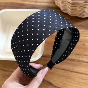 Detail view of the black wide headband with white polka dots and non-slip inner teeth