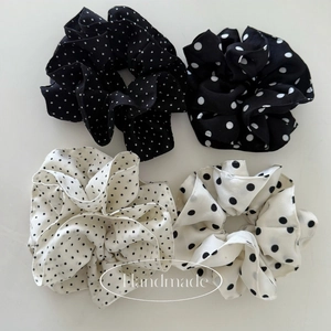 Detailed view of four handmade polka dot scrunchies in classic black and white patterns