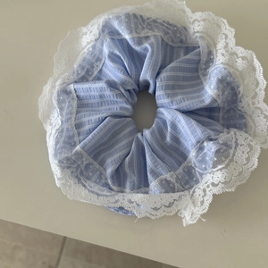 Nahaufnahme eines blau-weiß gestreiften Stoff-Scrunchies mit zarten weißen Spitzenkanten