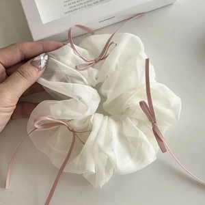 Detail van een grote organza scrunchie met geplooide tule en roze lintstrikken