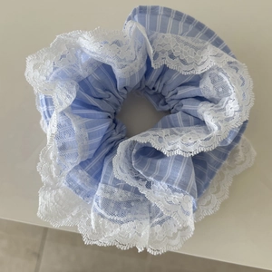 Nahaufnahme von hellblau gestreiftem Haargummi mit weißer Spitze und Zierdetails