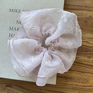 Close-up of pink mesh hair scrunchie with white bow and floral embroidery details