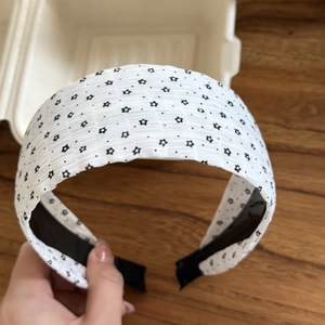 Detail of white wide fabric headband with black star patterns and anti-slip lining