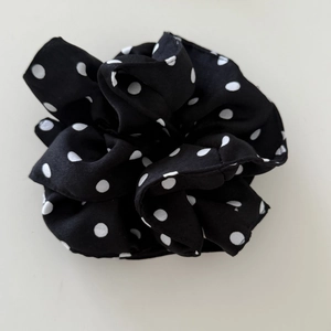 Macro detail of high-quality black fabric scrunchie with white polka dot patterns