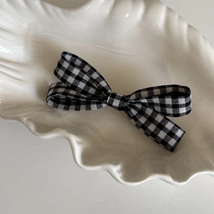 Detail einer schwarz-weißen Gingham-Schleife Haarspange auf einer Dekorschale