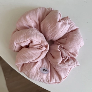 Close-up of light pink oversized scrunchie featuring textured fabric and a bow tag detail
